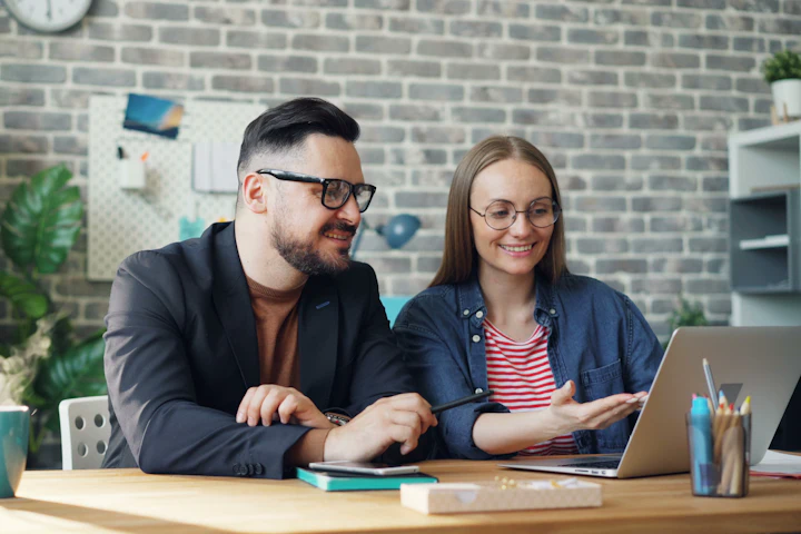 Two colleagues looking at a laptop together and smiling
