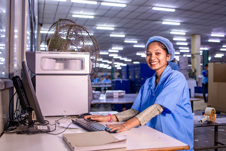 A smiling worker at a computer on a factory floor