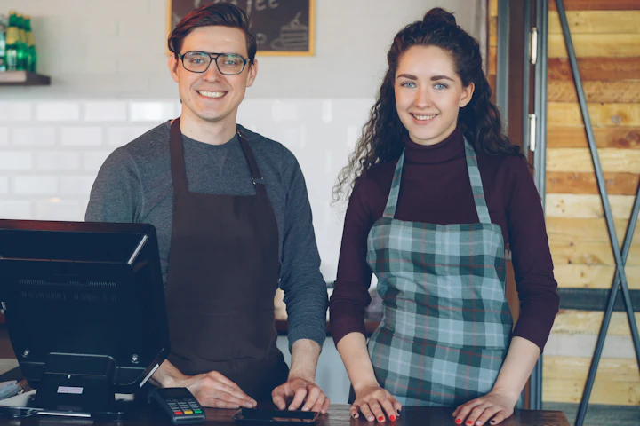 Two smiling café owners behind their counter