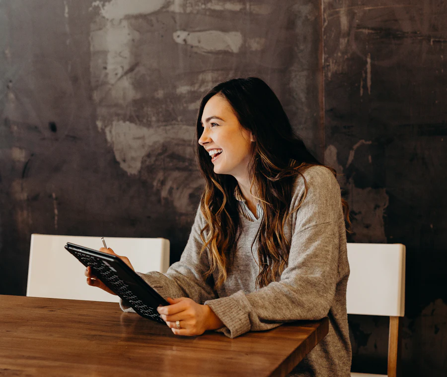 A smiling woman filling in a form on a tablet